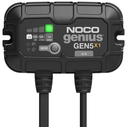 NOCO Genius On-Board Chargers device with a black rugged casing, LED indicators showing charging status, and two connected cables for power input and output.